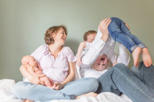 family of four playing on the bed for their newborn photos