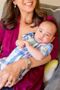 mom holding newborn baby for what to wear newborn photos of mom wearing a colorful blouse and the baby wearing plaid