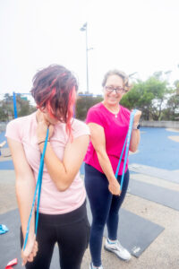 personal trainer showing resistance bands to a client at the park for group training