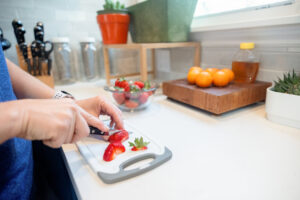 close up photo of person cutting strawberries on a small cutting board