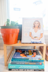 photo of cookbooks and workout books in the kitchen with plants next to the books