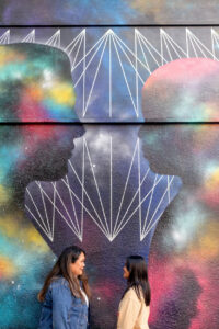 mom and daughter looking at each other in front of a mural in downtown los altos