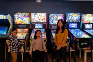 three kids standing in front of pinball machines inside state of mind pizza in los altos for their family photos