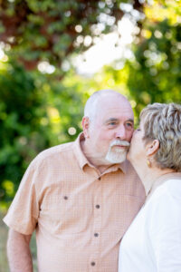 mom and dad giving each other a kiss for a wedding anniversary photos session at the park