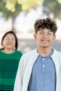 boy looking at the camera with mom in the background
