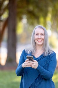 woman holding a phone and looking at the camera for fall headshot photos