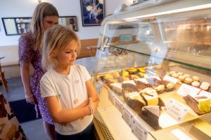 little girl looking at a bakery window